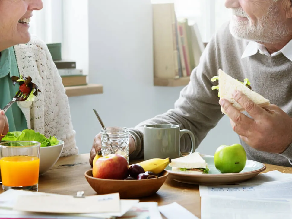 Un couple de personne âgée heureux partagent un repas autour de la table