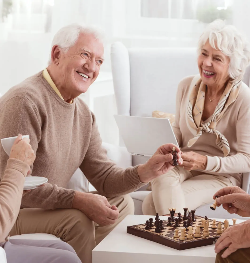 Un couple de personnes âgées heureux jouant aux échecs au Résidences de la Providence