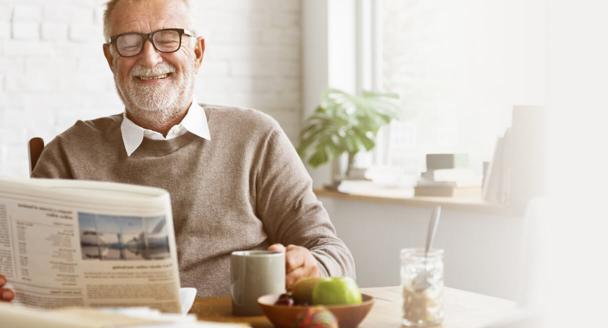 Un grand-père serein et souriant tenant un journal